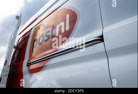 A van on the road with the logo of the Dutch postal company 'PostNL'. Courier company in the Netherlands. Side view with open rear door Stock Photo