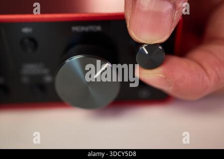 Adjusting audio controls, Precise handling of control knobs on audio equipment during setup, Fingers align control dials on audio interface for Stock Photo