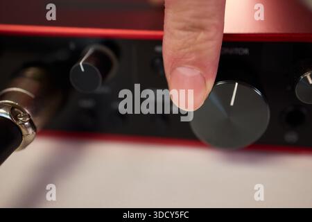 Adjusting audio controls, Precise handling of control knobs on audio equipment during setup, Fingers align control dials on audio interface for Stock Photo
