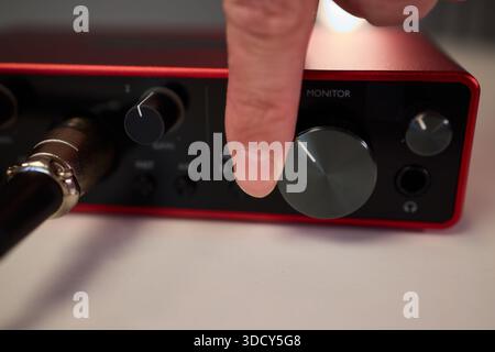Adjusting audio controls, Precise handling of control knobs on audio equipment during setup, Fingers align control dials on audio interface for Stock Photo