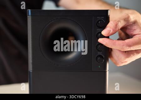 Adjusting bass knob in listening space, Technician modifies subwoofer settings in cozy setup, Close examination of audio equipment controls under warm Stock Photo