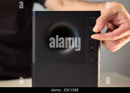 Adjusting bass knob in listening space, Technician modifies subwoofer settings in cozy setup, Close examination of audio equipment controls under warm Stock Photo