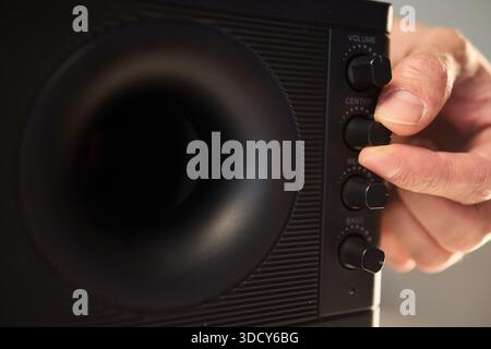 Adjusting bass knob in listening space, Technician modifies subwoofer settings in cozy setup, Close examination of audio equipment controls under warm Stock Photo