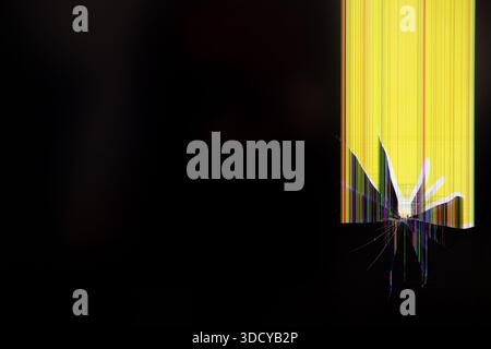 Close-up view of a broken electronic screen with a distinct impact point, displaying bright vertical color lines, ideal for illustrating technology fa Stock Photo