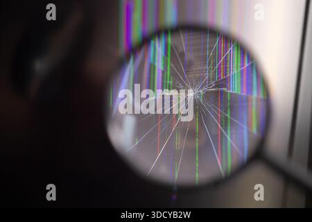 Focused view of a severely fractured digital screen, highlighting a spiderweb crack pattern alongside vertical pixel distortions, illustrating device Stock Photo