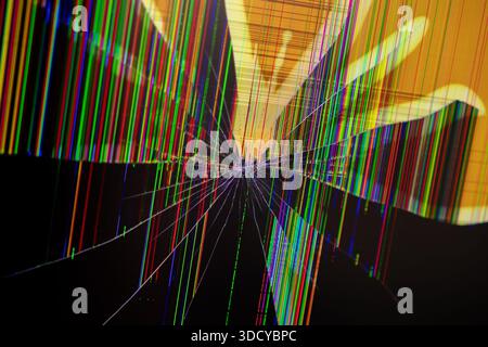 Close-up of a damaged digital screen showing chaotic vibrant multicolored lines and radiating cracks, representing display malfunction, system error, Stock Photo