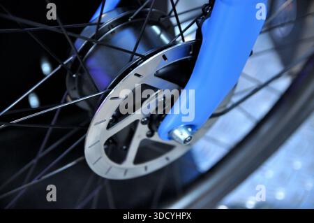 Close-up view of a front disc brake, wheel hub, and front fork of an urban electric bicycle. Stock Photo