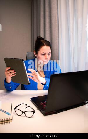 Online business owner managing her e-commerce store from home. Entrepreneur analyzes data on computer screen in home setting. Modern reality of runnin Stock Photo