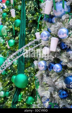 Close-up of decorated Christmas trees with blue and green ornaments, lights, and holiday cups. Stock Photo