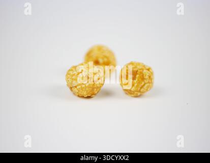 Close up of golden caramel popcorn texture on clean white surface. Minimal sweet crunchy snack composition for cinema advertising and food design Stock Photo
