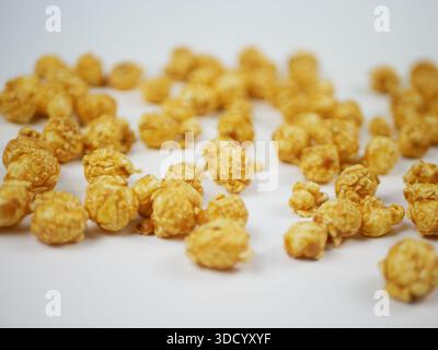 Side view of a pile of caramel popcorn balls on white table with soft blur, sweet crunchy snack concept for cinema food, branding and clean background Stock Photo