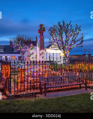 A view at dusk at Christmas of the Christmas Lights display in the village square war memorial on the Holy Island of Lindisfarne in Northumberland Stock Photo