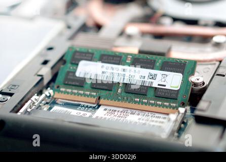 Captures the process of installing a new memory stick, shown at a 45-degree angle in the slot before being pressed down. Perfect for "how-to" upgrade Stock Photo