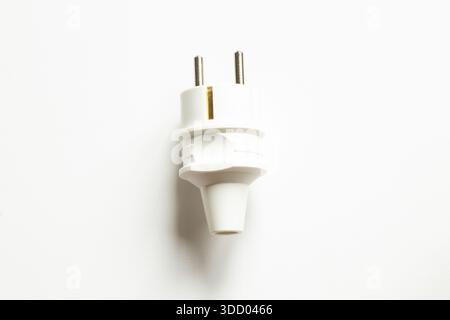 White electric plug with two metal contacts, isolated on a clean white background, minimalism, household electronics, safety and network connection Stock Photo