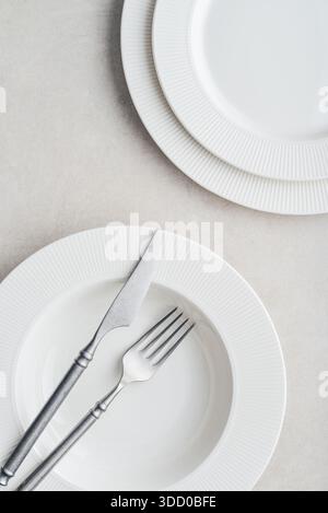 Clean plates, vintage fork and knife on light background, top view. Space for text Stock Photo