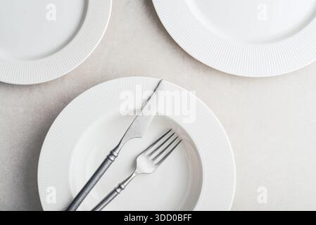 Clean plates, vintage fork and knife on light background, top view. Space for text Stock Photo