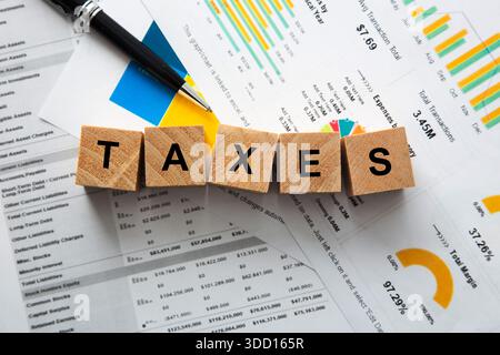 Taxes word spelled out on wooden blocks, spreadsheet, chart, and pen representing finance Stock Photo