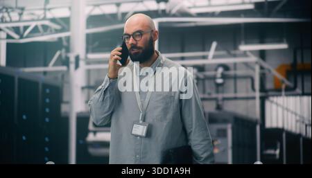 Data Center Manager Taking Critical Business Call. IT Specialist in Server Hall Handling Critical Business Call on Smartphone. Concept Client Liaison and Professional Communication in IT Management. Stock Photo