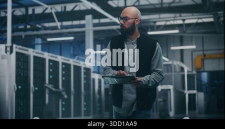 Engineer Utilizing Software in Data Center. Professional Male Engineer Uses Specialized App on Tablet to Monitor Performance of Enterprise Level Servers. Modern IT Tools and Technical Supervision. Stock Photo