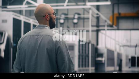 IT Specialist Conducting Physical Server Hall Inspection. Professional Engineer Walks Purposefully Through Massive Data Center Hall, Conducting Visual and Physical Inspection of Infrastructure Scale. Stock Photo