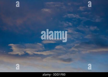 High-altitude view of a dramatic twilight sky showing deep blue and violet tones with soft, misty clouds and subtle light gradients. Stock Photo