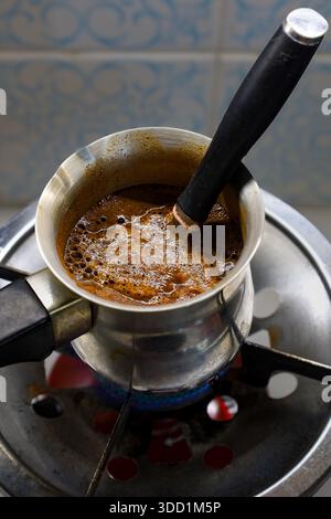 A traditional Greek briki is used to prepare rich coffee over a gas burner Stock Photo