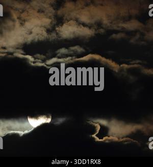 Bright full moon peeking between hearvy clouds at night over North Carolina. Stock Photo