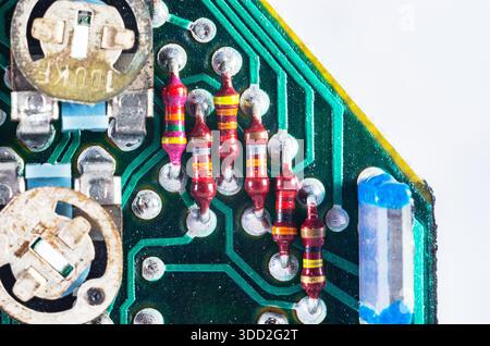 Close-up macro shot of electronic components on a green circuit board with resistors and potentiometers Stock Photo