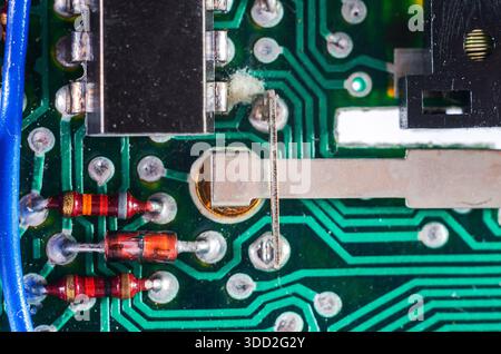 Close-up view of electronic components on a green circuit board with resistors and wires Stock Photo