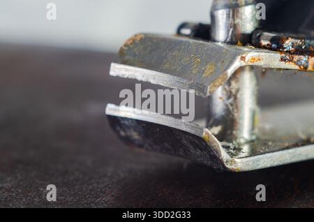 Extreme close-up of a rusty staple remover tool on a dark surface Stock Photo