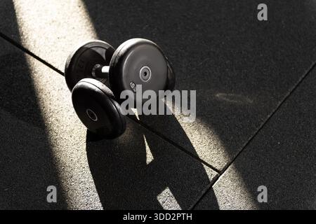 Close up photo of two 5kg dumbbells stacked on top of each other illuminated by dappled sunlight Stock Photo