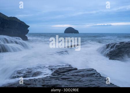 Waves break over the rocks at Trebarwith Strand looking out towards Gull rock on the north Cornwall coast. Stock Photo