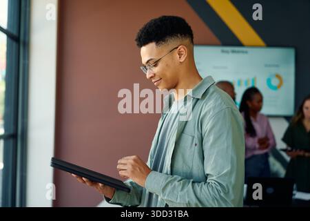 Confident young businessman in smart casual using tablet in boardroom at office during daytime Stock Photo