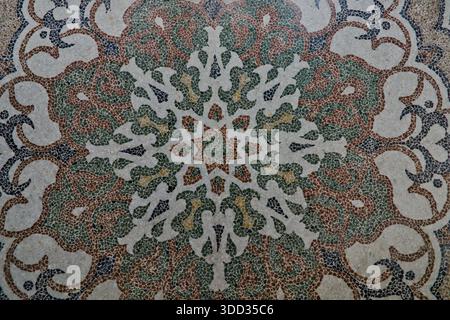 A close-up of a detailed, colorful mosaic floor or wall pattern, featuring a complex symmetrical floral and geometric star design. Stock Photo