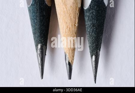 Close-up of the sharp tips of three graphite pencils placed close to each other, white background, macro Stock Photo
