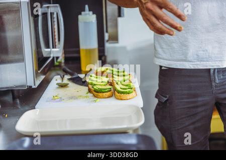 Vegan chef preparing avocado toast in restaurant kitchen workstation. Stock Photo