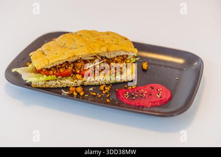Vegan avocado tomato rocket toast with beet hummus on black plate. Stock Photo