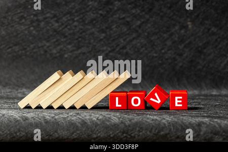Love problems. Disappointment, the breakdown of feelings. The domino effect knocks over red blocks with the word Love written on them. The concept of Stock Photo
