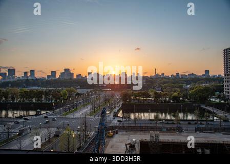 Warm sun sets behind Tokyo’s skyline, silhouetting towers above the Imperial Palace moat and tree-lined avenues. Stock Photo