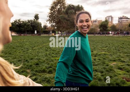 Diverse woman joyfully smiling with friend in park Stock Photo