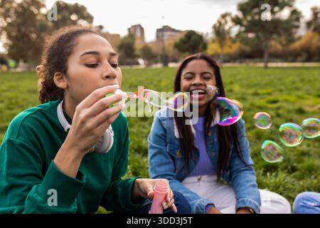 Happy friends blowing bubble making soap bubbles in park Stock Photo