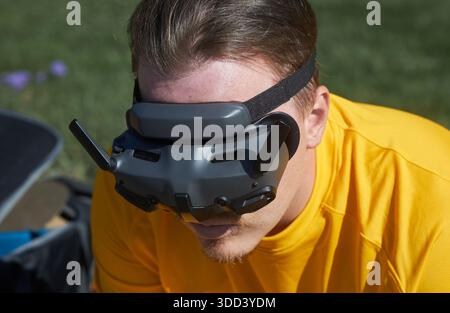 Man with brown hair wearing DJI drone FPV goggles outdoors for remote flying experience. Technology and virtual reality for recreation. Bishkek, Kyrgy Stock Photo