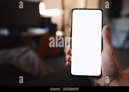 POV photo of man holding smartphone with white screen while sitting on a couch Stock Photo