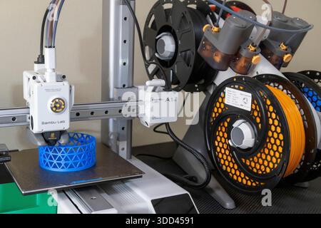 A close-up of a Bambu Lab 3D printer crafting a blue lattice cylinder. The printer head and emerging structure are sharply focused, ideal for illustra Stock Photo