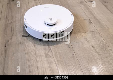 Robotic vacuum cleaner cleaning a wooden floor Stock Photo