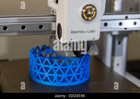 The 3D printing process progresses as the lattice-patterned cylinder takes shape. The printer head is visible in action, emphasizing precision and des Stock Photo