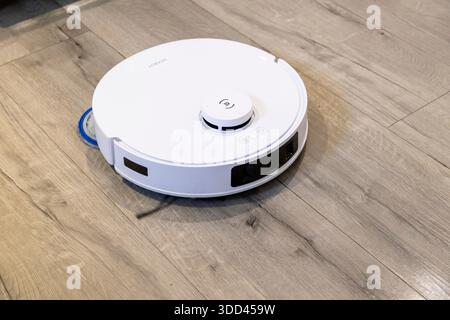 Robotic vacuum cleaner cleaning a wooden floor Stock Photo