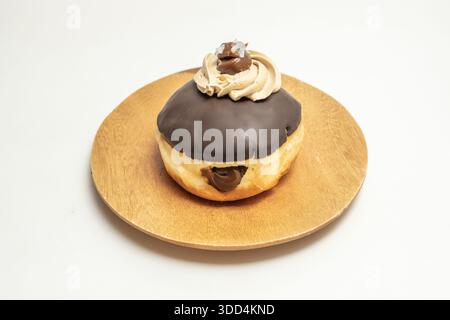 A chocolate Berliner with a soft brioche dough, filled with milk chocolate ganache and covered with a glossy chocolate fondant glaze Stock Photo