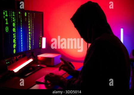 An expert hacker is decrypting data while hiding their face || Model released Stock Photo
