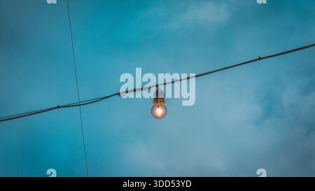 Close-up of warm yellow vintage  bulb glowing in the dark evening at a festival Stock Photo